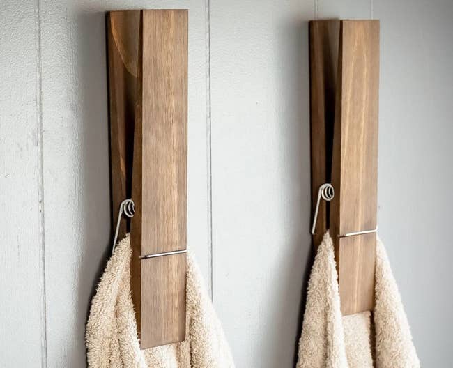 two giant clothespins on a wall and holding towels