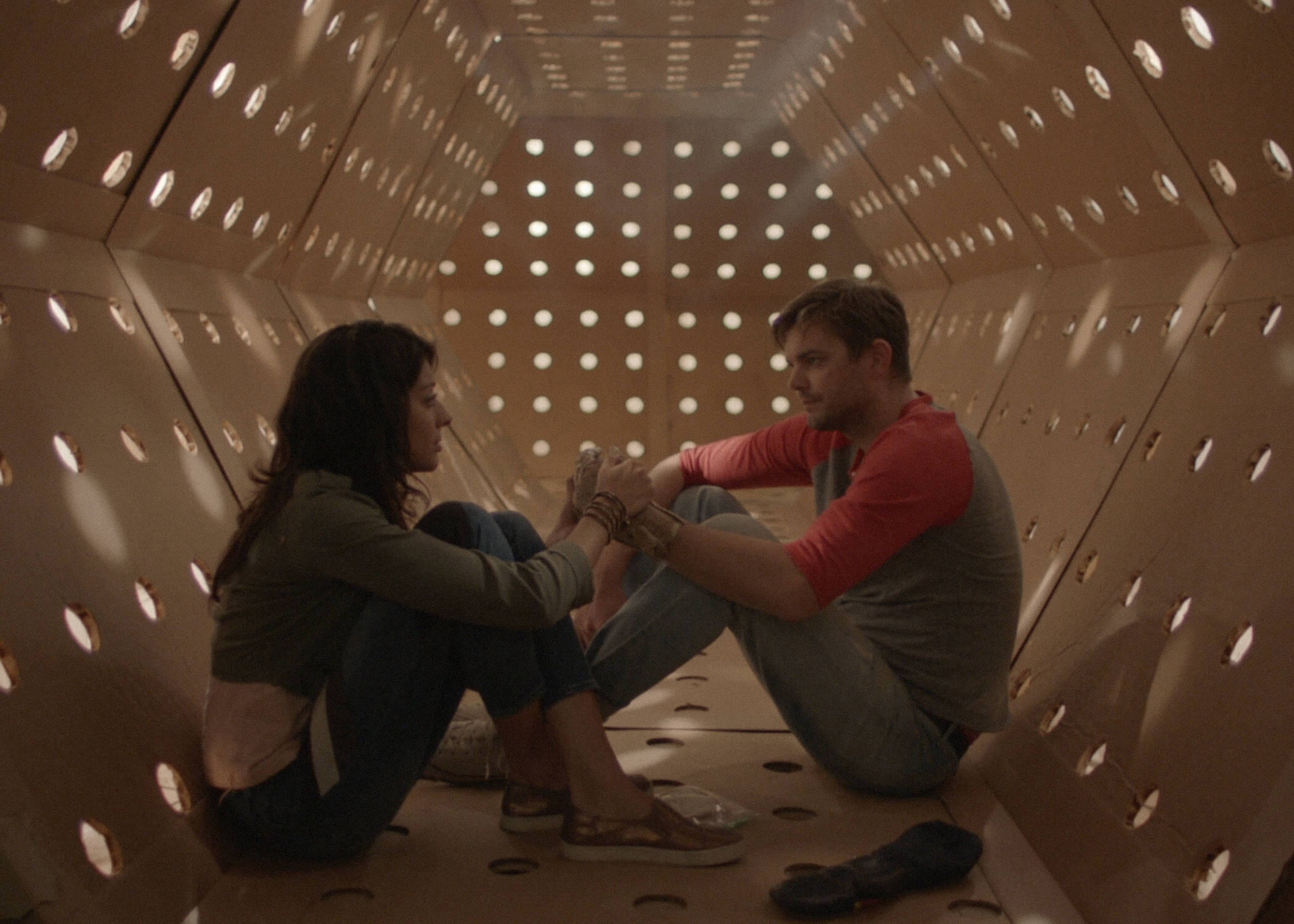 Meera Rohit Kumbhani and Nick Thune sit inside the cardboard maze