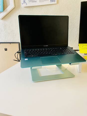 same laptop stand in a blue shade with a laptop on a white desk