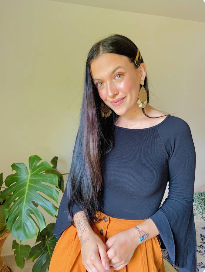 A woman with tattoos on one arm smiles at the camera