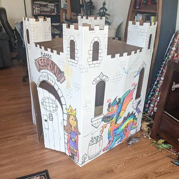 Reviewer showing the cardboard fairytale castle their children colored