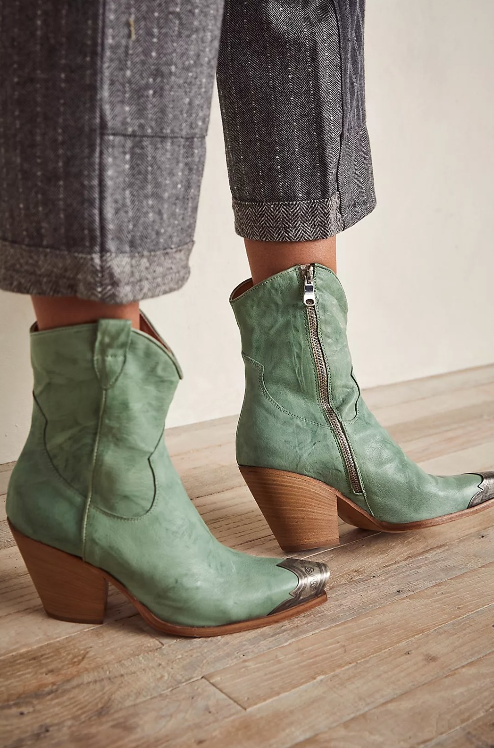 model wearing the green ankle-high cowboy boots with gray pants