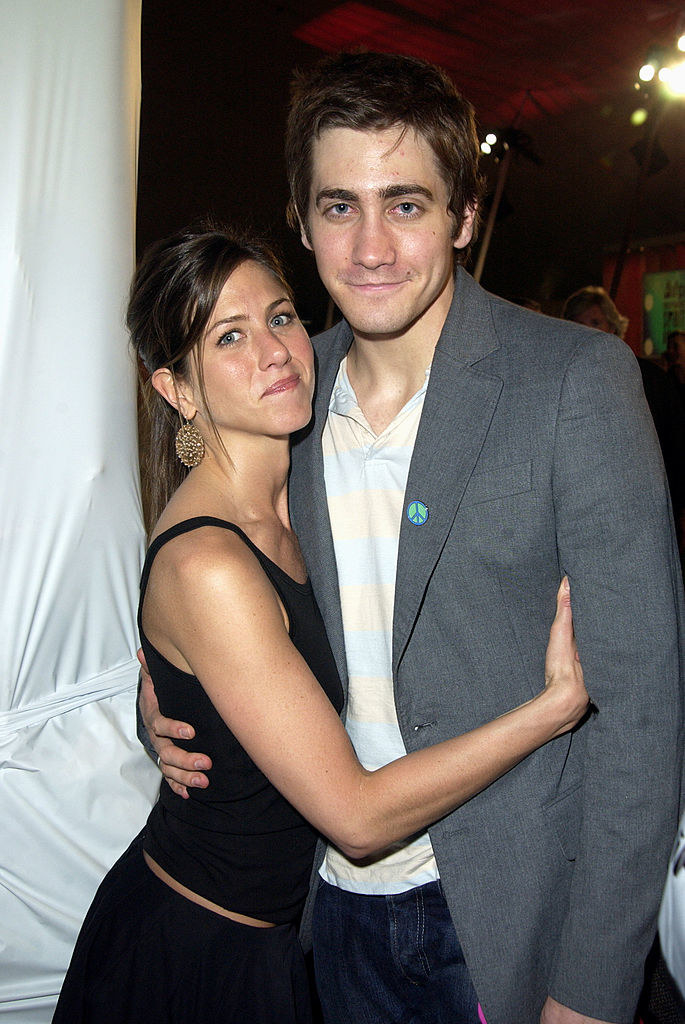 Jennifer Aniston and Jake Gyllenhaal (R) smiling for the camera with their arms around each other
