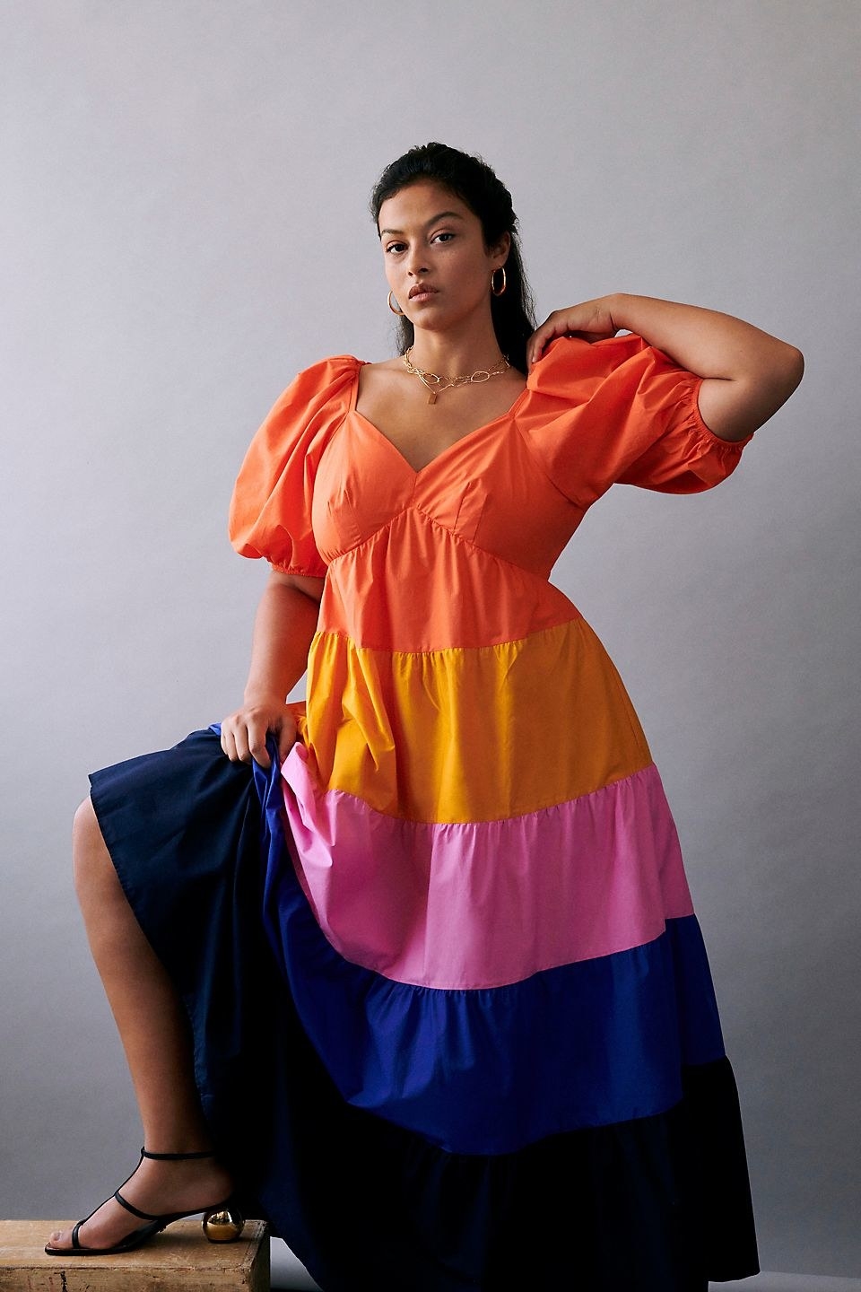 model wearing the maxi dress in orange, yellow, pink, blue, and dark navy with purff-sleeves