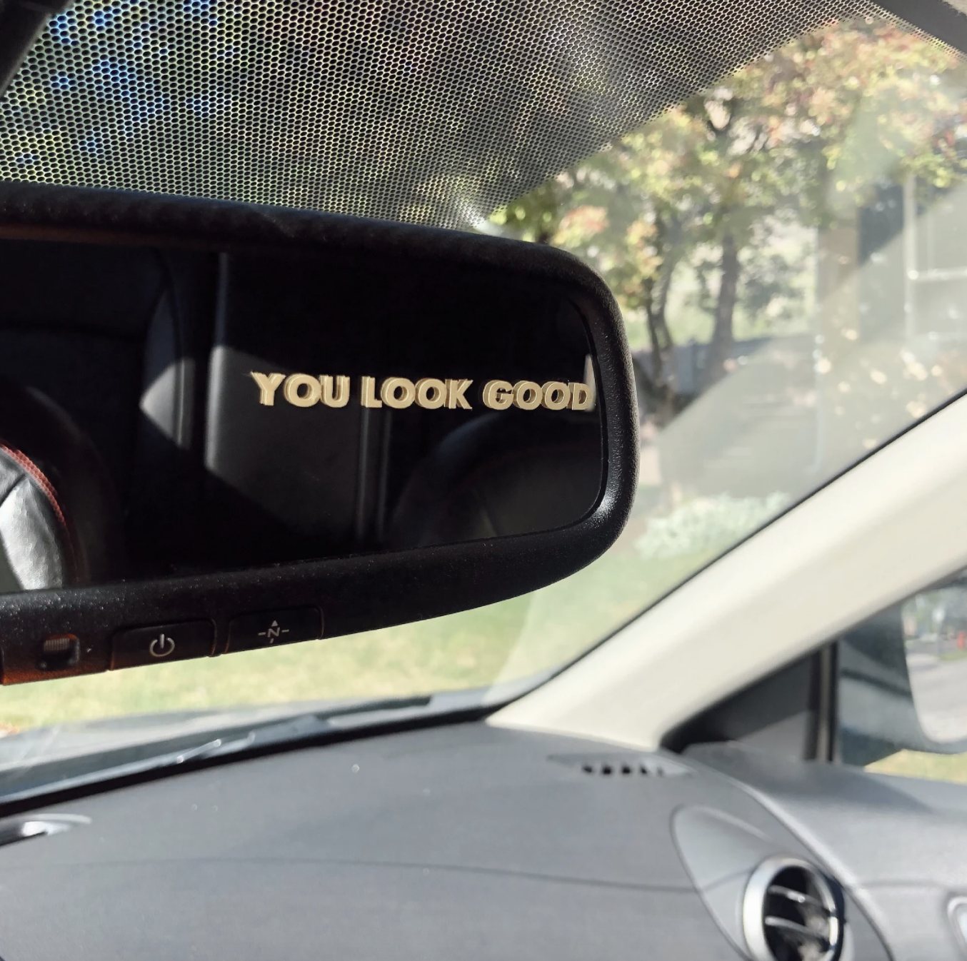 The decal on a rear view mirror that reads, &quot;you look good&quot;