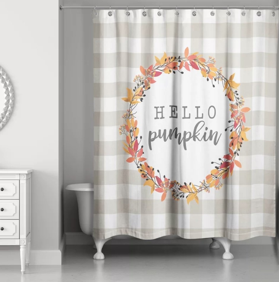 A beige/white checkered shower curtain with a colorful fall wreath design and "Hello pumpkin" written in the center