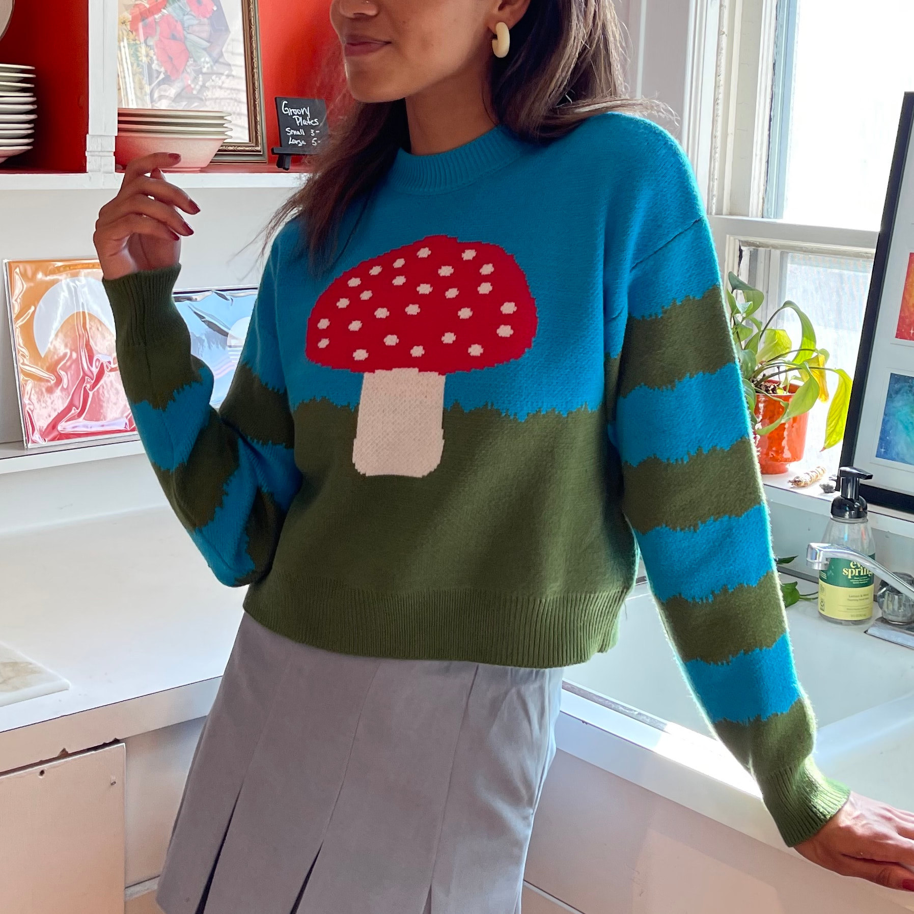 model wearing the blue and green sweater with red and white mushroom on it
