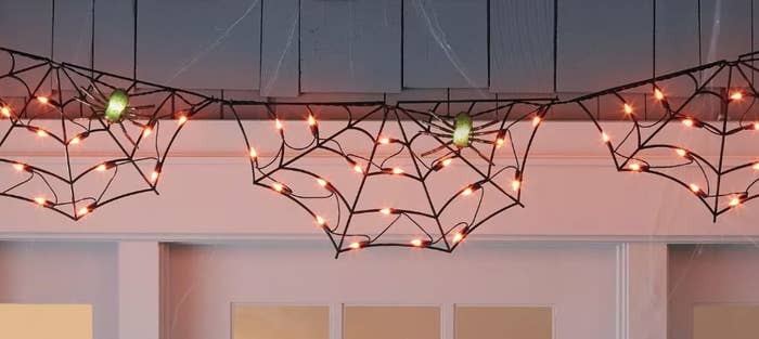 Black spider web hanging lights with orange lights and green light up spiders