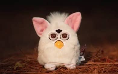 a white furby on some grass staring into the abyss