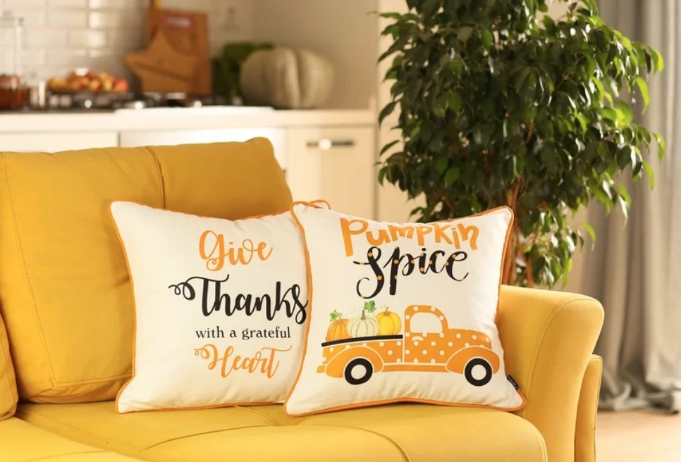 A set of two orange/white fall-themed throw pillows with "give thanks with a grateful heart" &amp;amp; "pumpkin spice" written on them