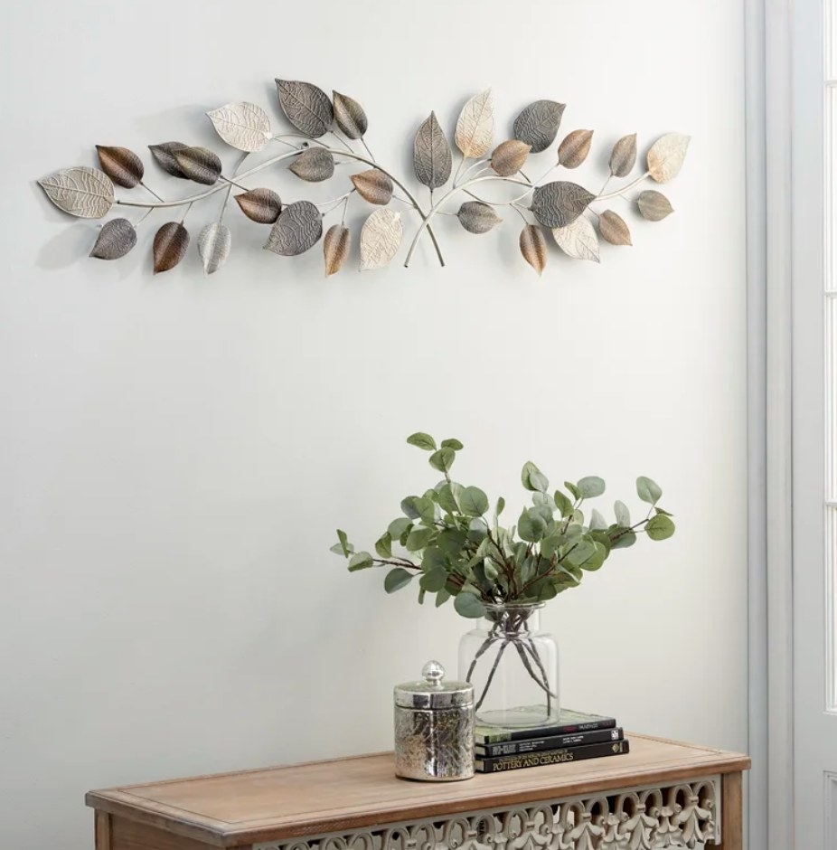 A silver/bronze metal, textured leaf wall decal above a entryway dresser