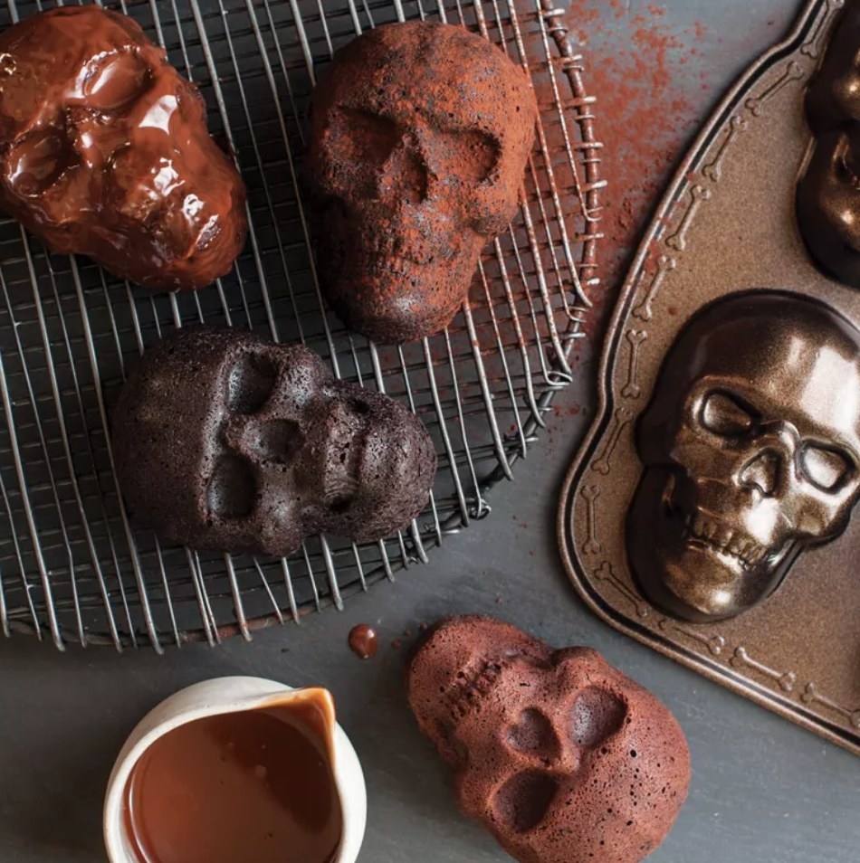 Skull shaped cakes next to bronze colored skull bake pan
