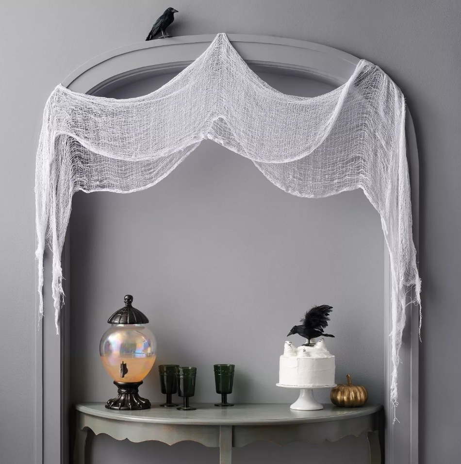 White cloth fabric draped over wall over console table with halloween decor