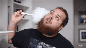 A guy pretending to clean his ear with a feather duster