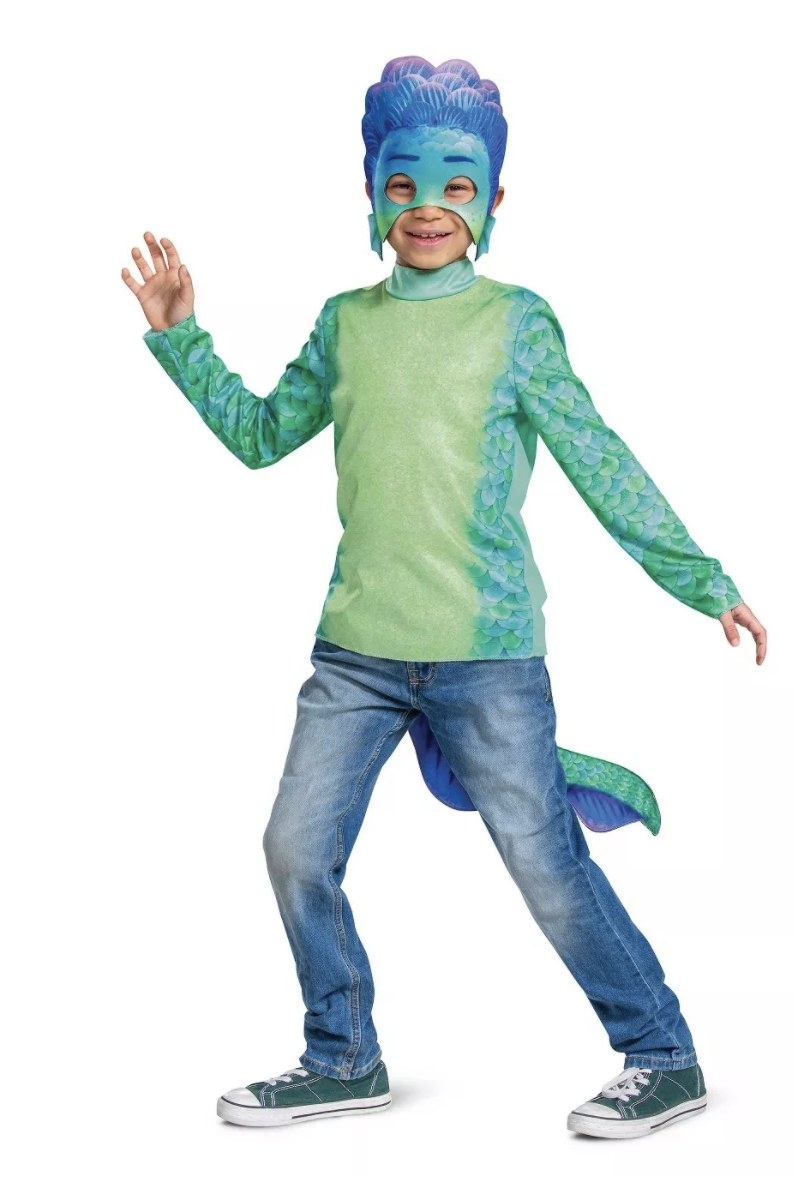 A child is wearing the green, blue and purple toned scale top, tail and half mask