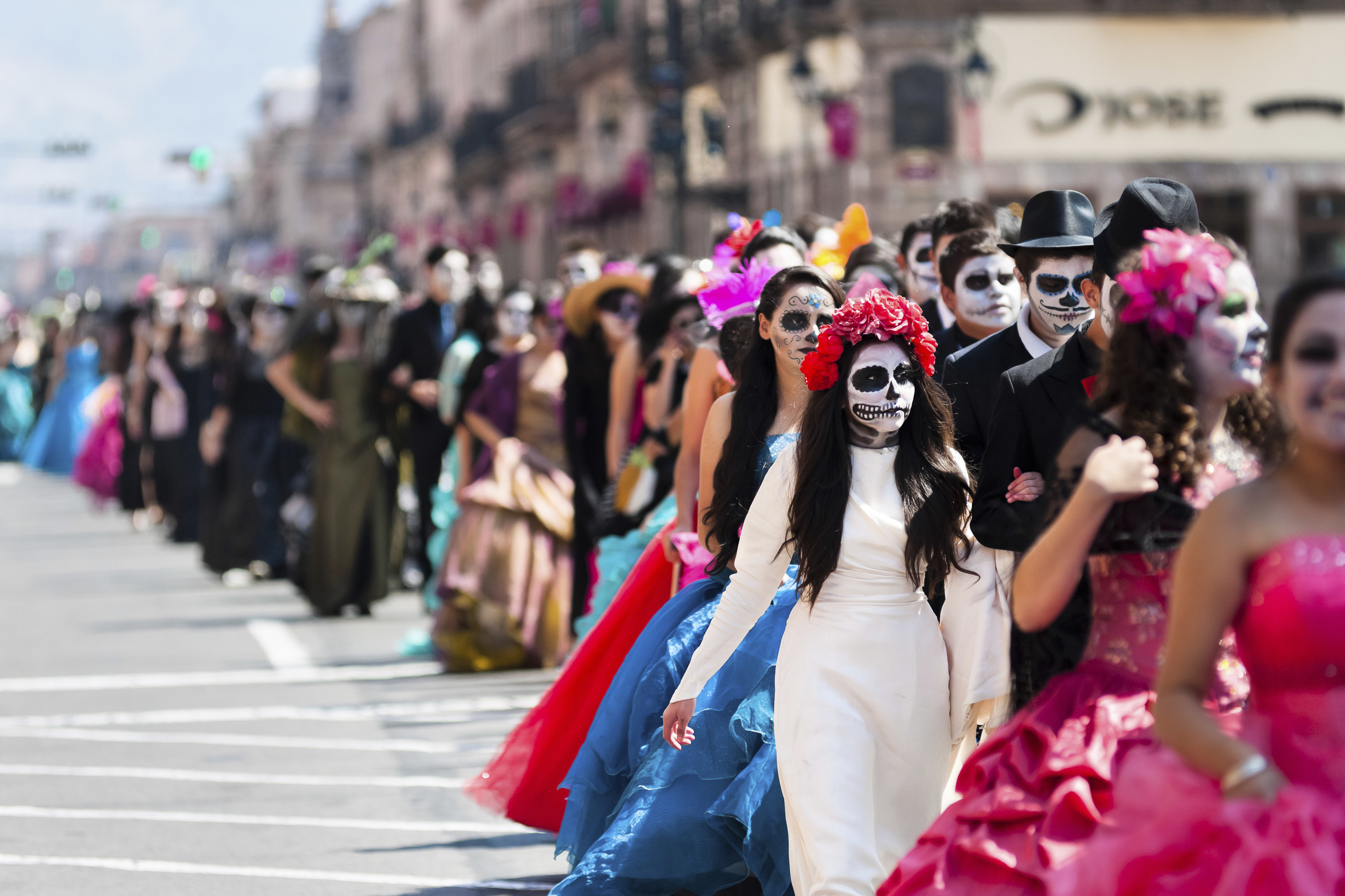 People in skull makeup and colorful costumes walking