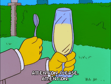 Someone tapping a champagne flute with a spoon and saying &quot;Attention, please. Attention&quot;