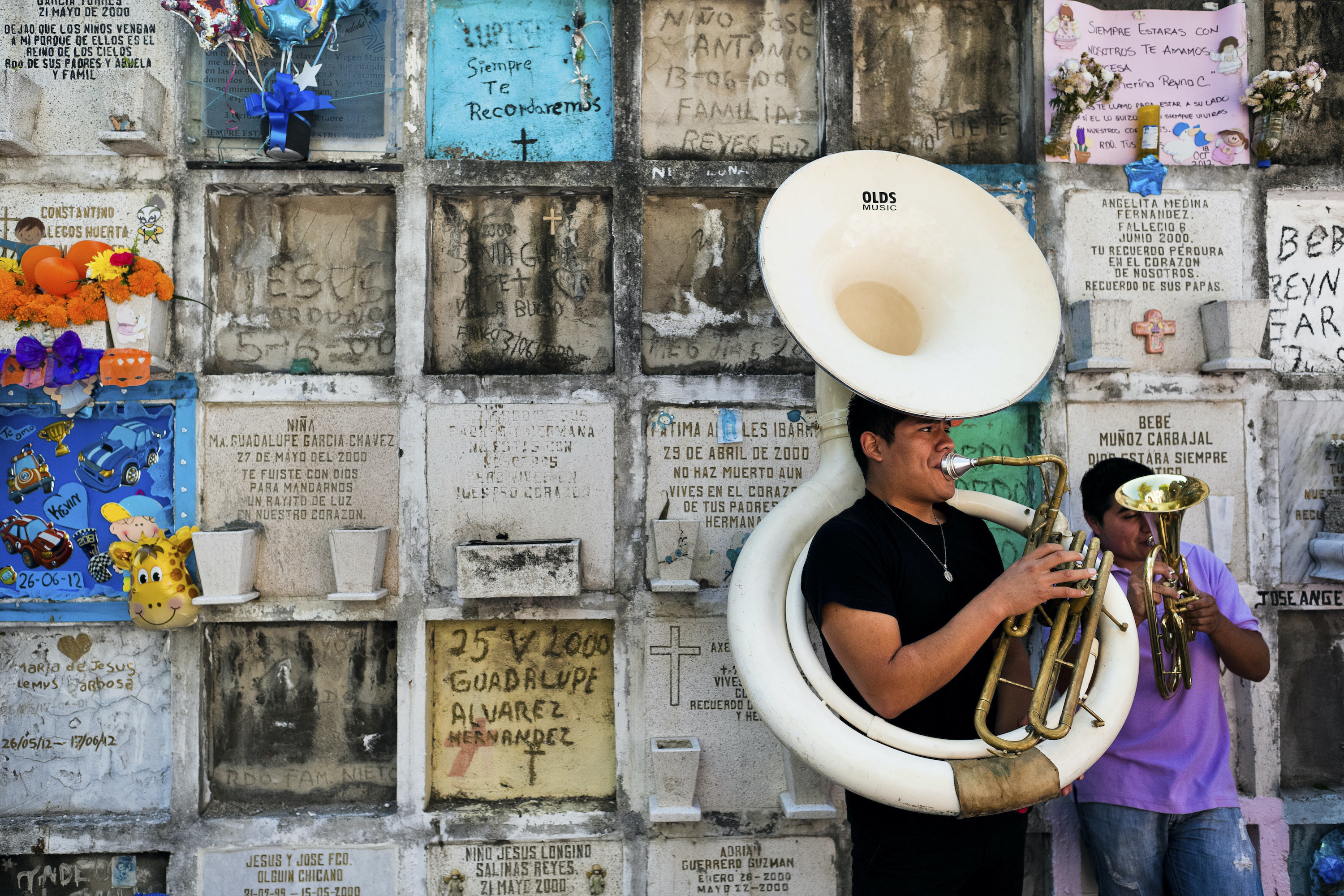 Two people perform next to a structure of vaults lined with recesses for urns