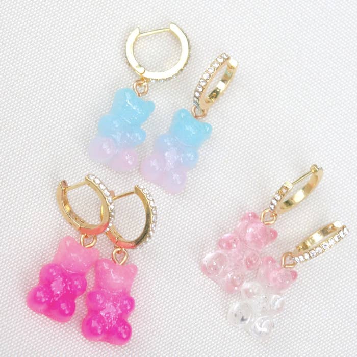three pairs of gummy bear huggies earrings in blue/pink, pink/white, and light pink/dark pink with crystals on the hoops
