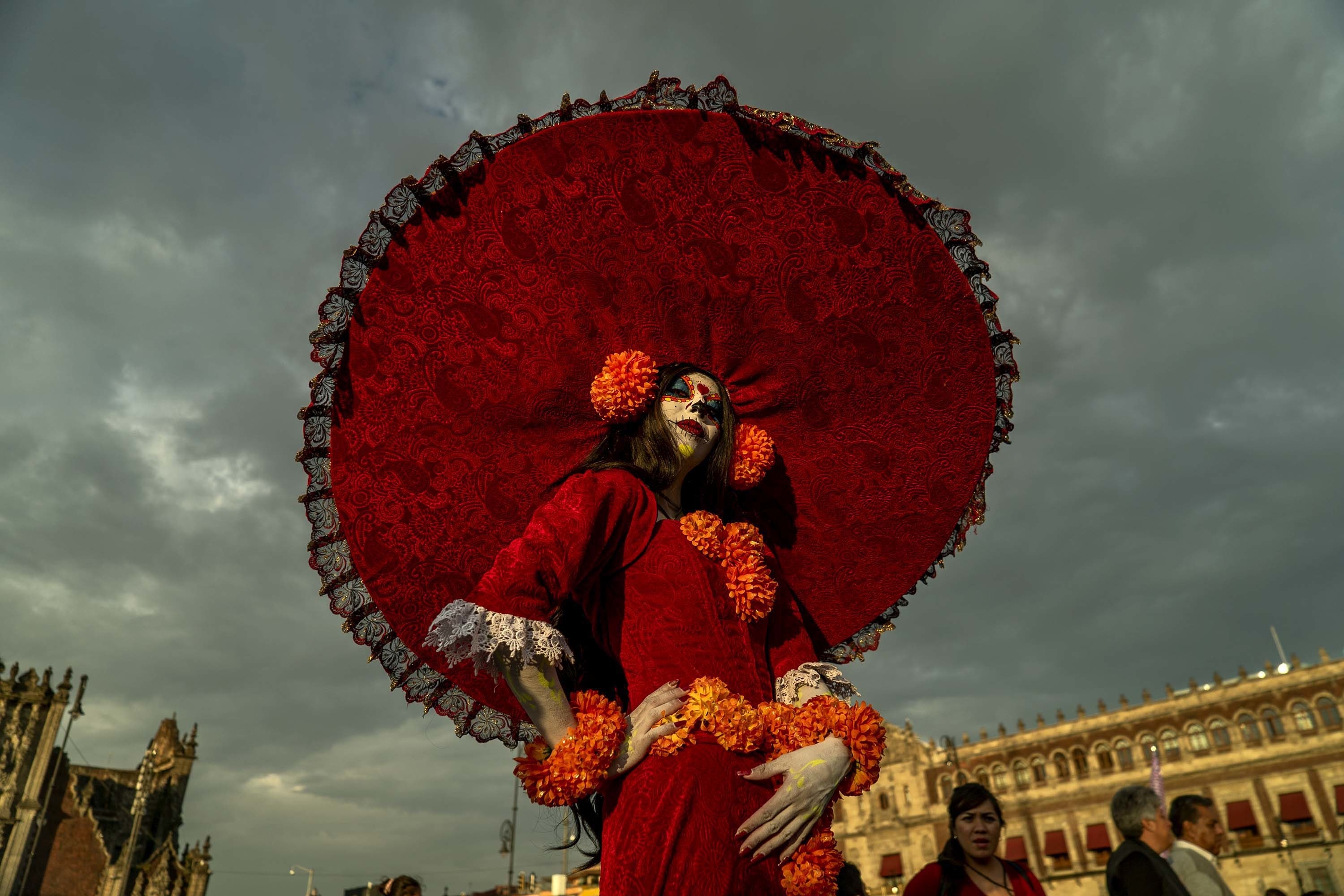 A person wearing a bright red outfit and large, wide-brimmed hat looks at the camera