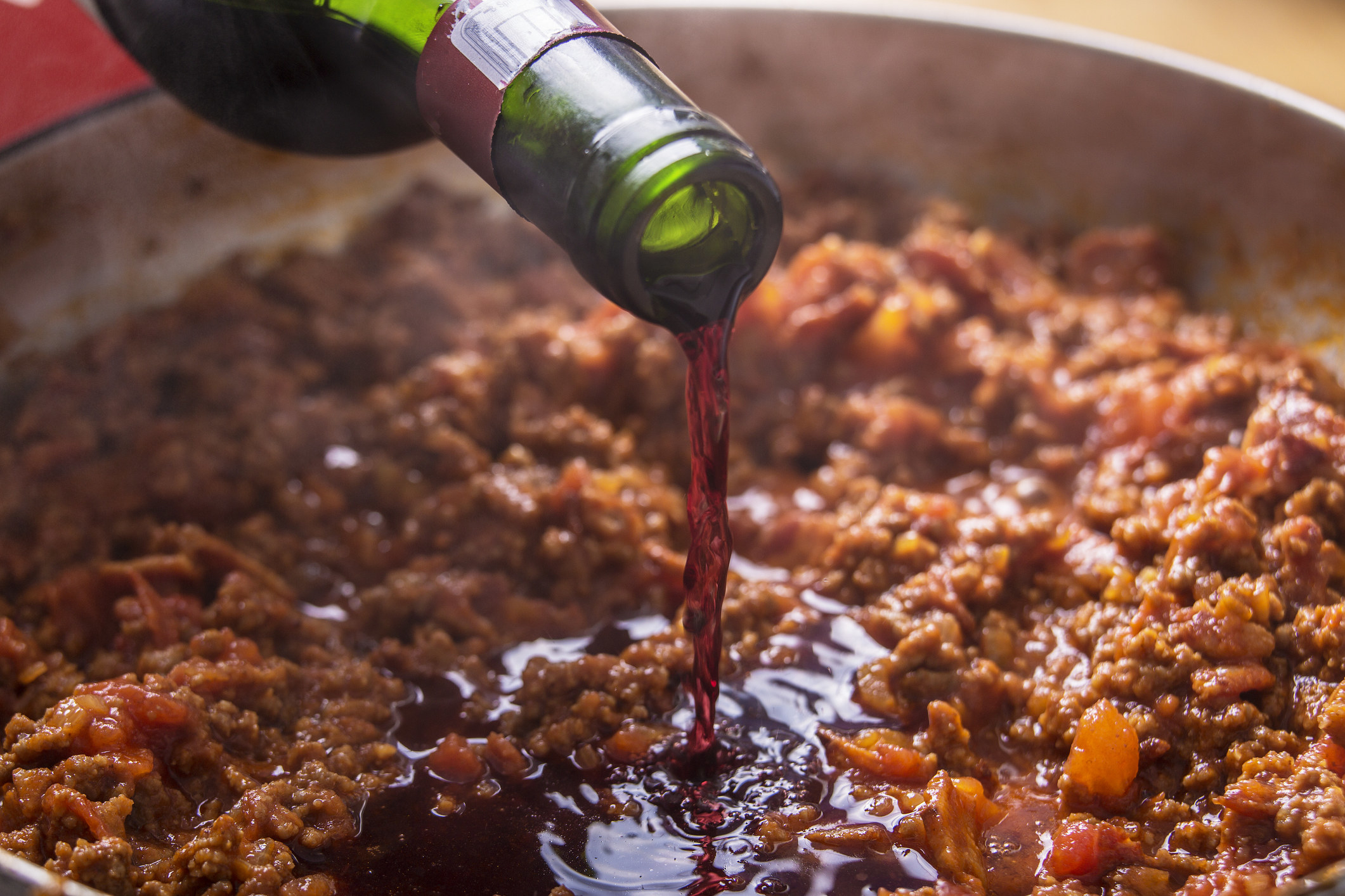 Pouring wine into ground beef.