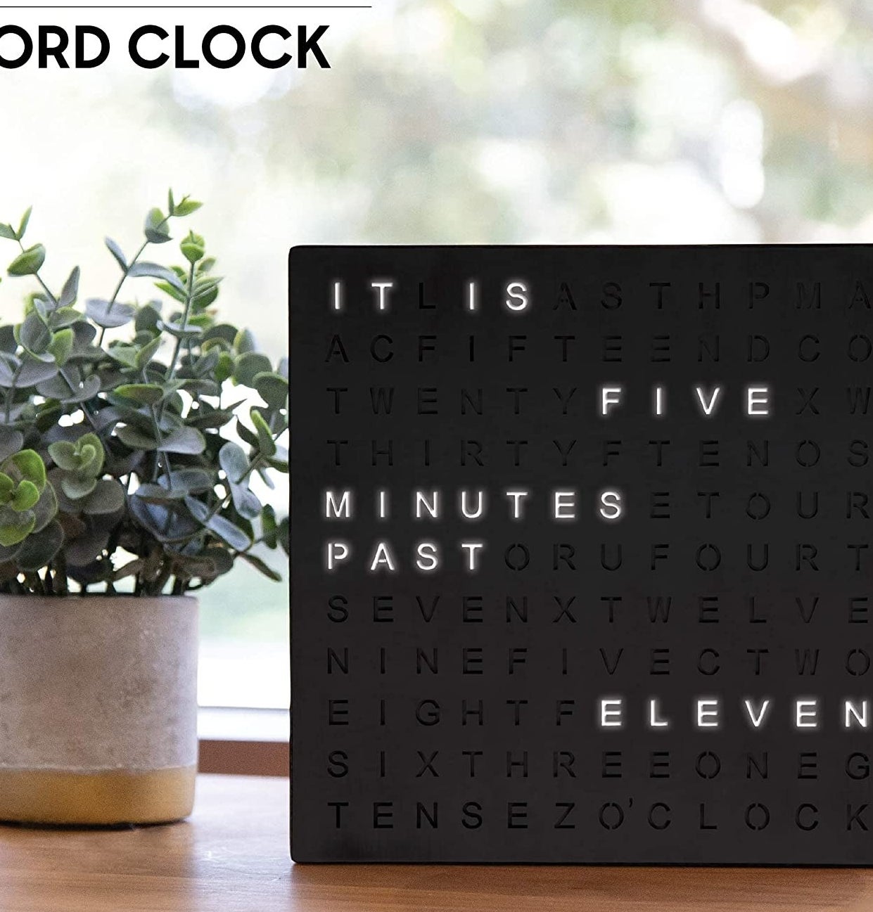 The clock on a desk beside a plant