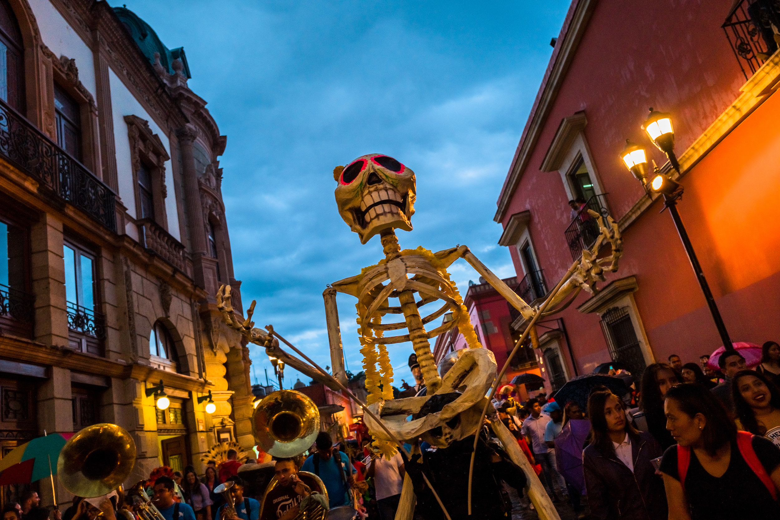 A large skeleton is elevated above the parade crowd
