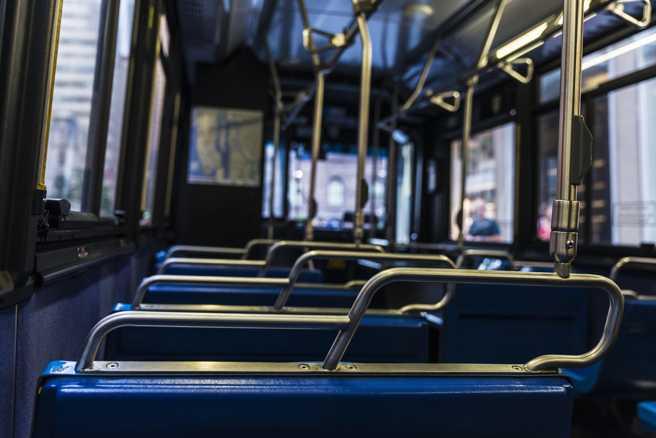 Empty blue seats with its metal handles inside a bus in New York