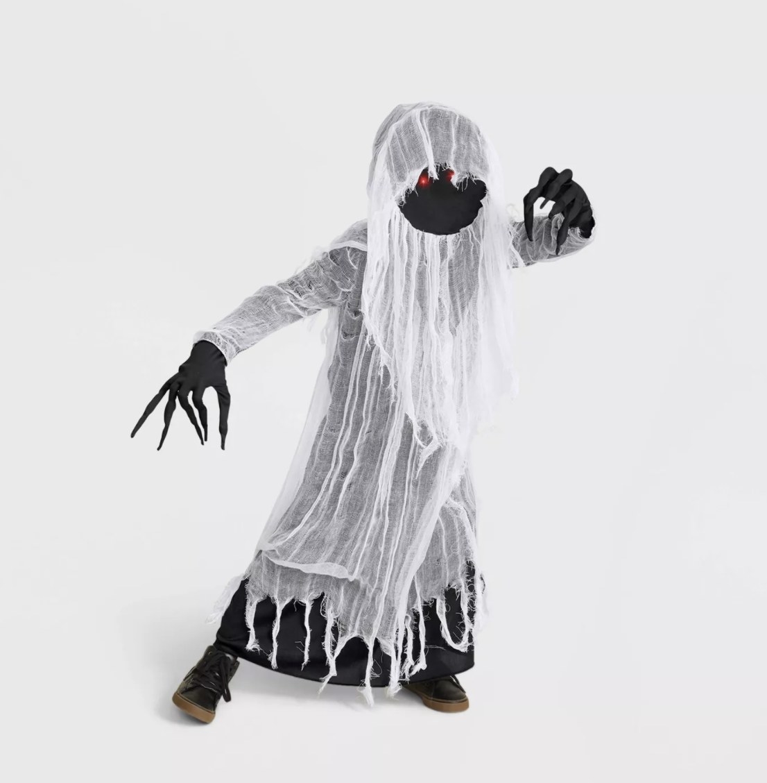A child is wearing a black robe with ripped white gauze, long black fingers and nails and red light-up eyes against a faceless covering