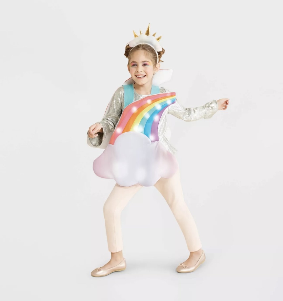 A child wears the lit up rainbow vest with a cloud at the bottom and a headpiece with a cloud  and gold spikes