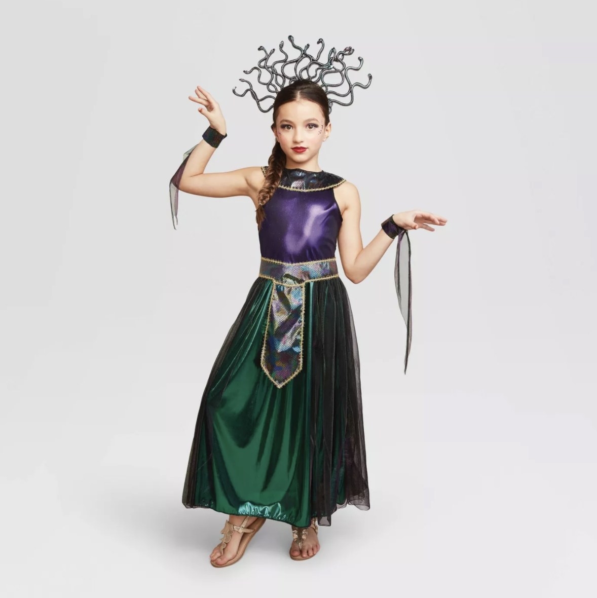 A child wears a green, black purple shiny medusa costume with draping armbands and a snake-like headpiece