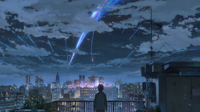 An anime clip of someone overlooking a city while flashing lights shoot from above