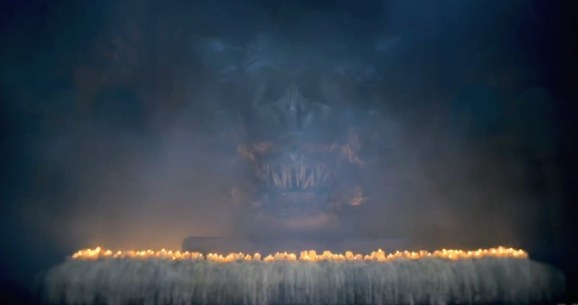 A dragon head is situated behind a row of burning candles