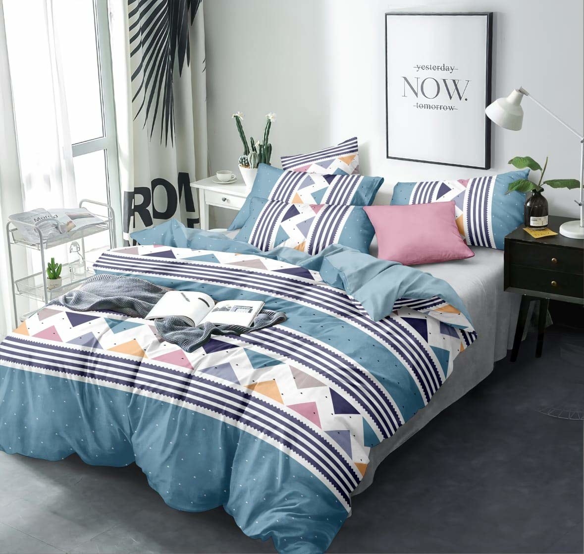 A comforter set on a bed with pillows and books on it