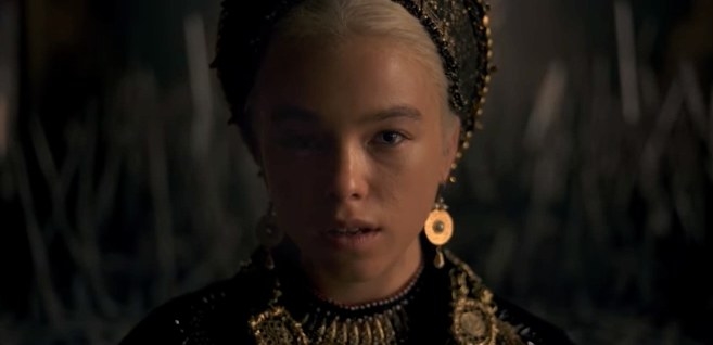 Rhaenyra stares into the camera with the throne behind her