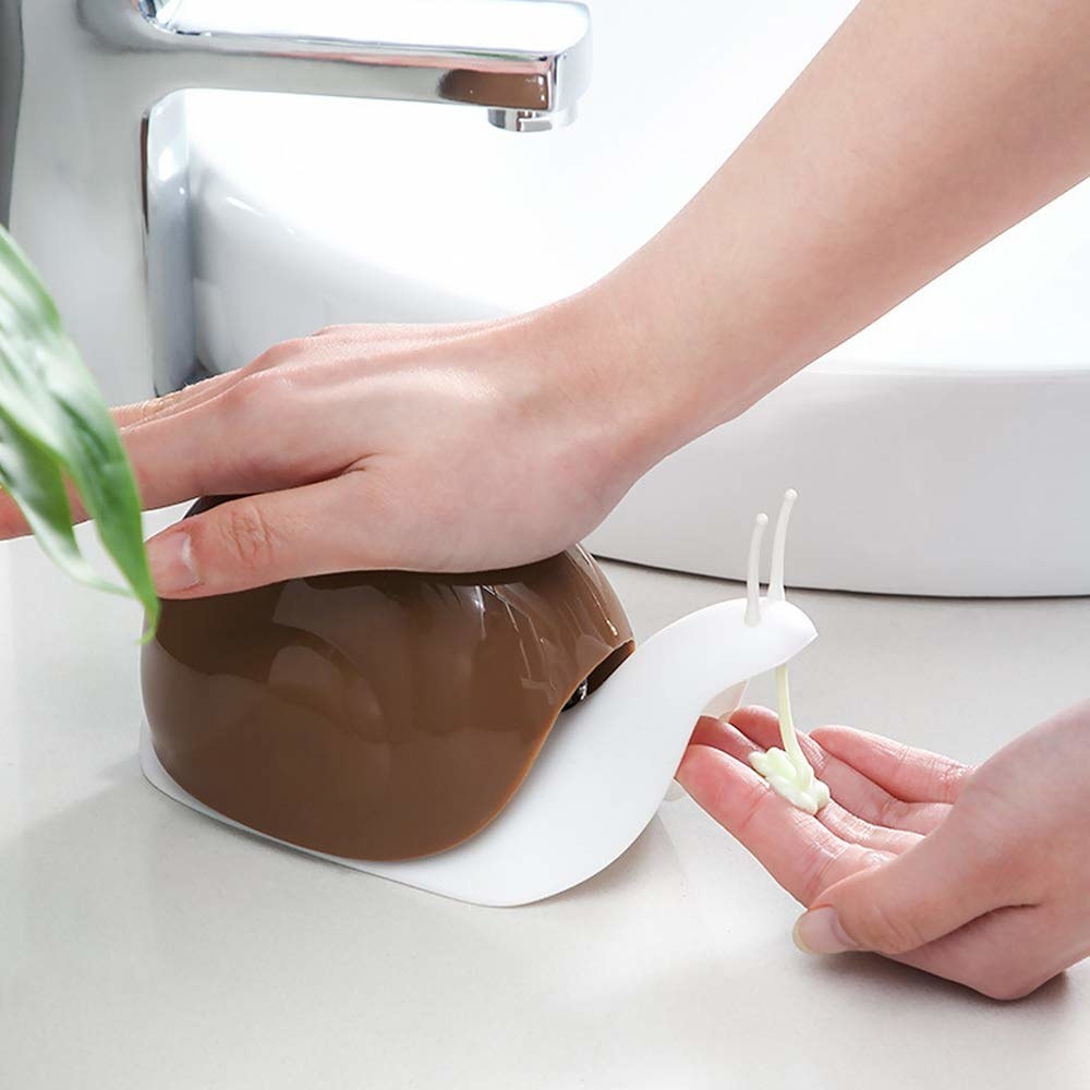 A person getting soap out of a snail soap dispenser