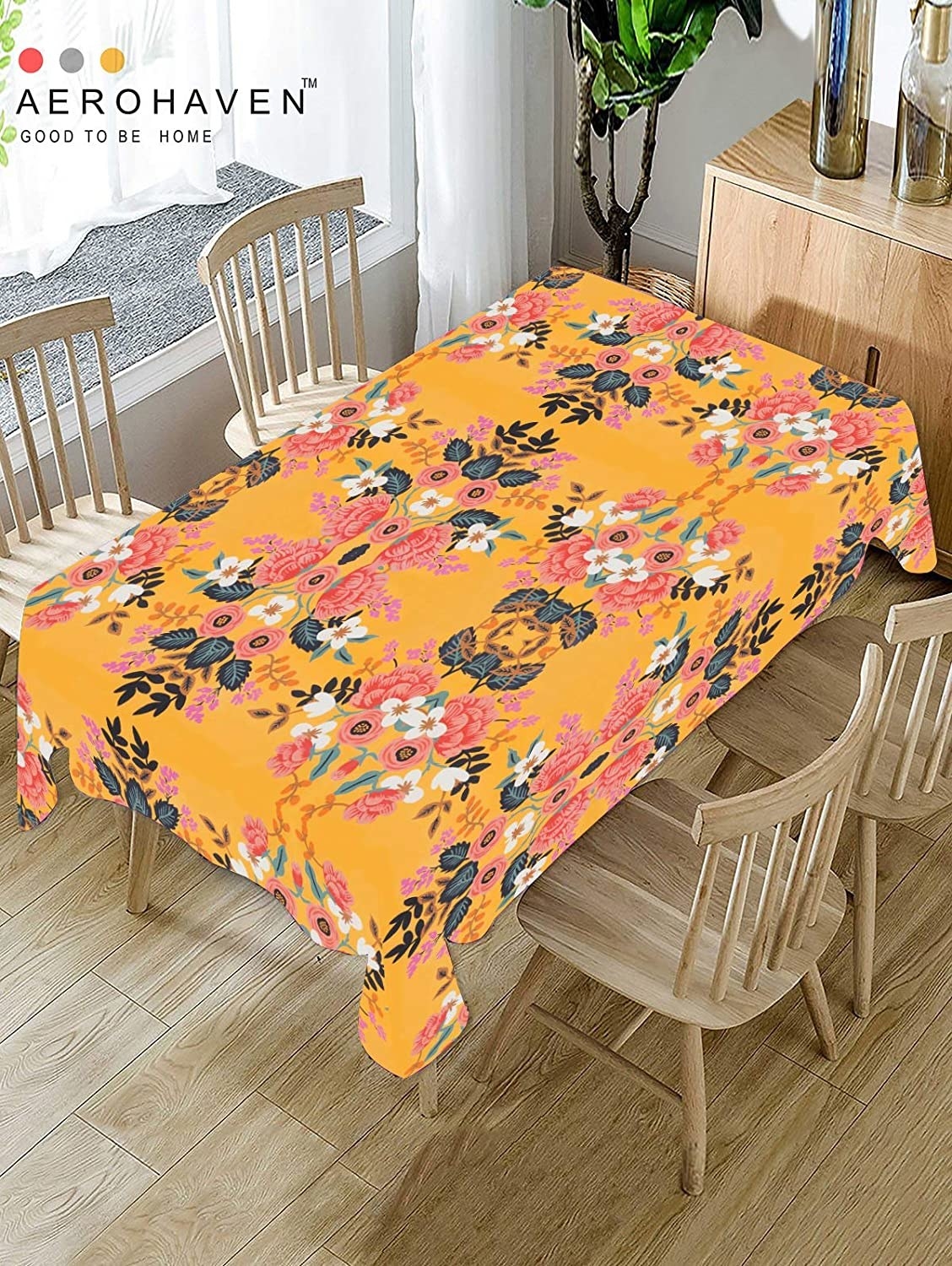 A yellow floral table cover on a table with chairs beside it