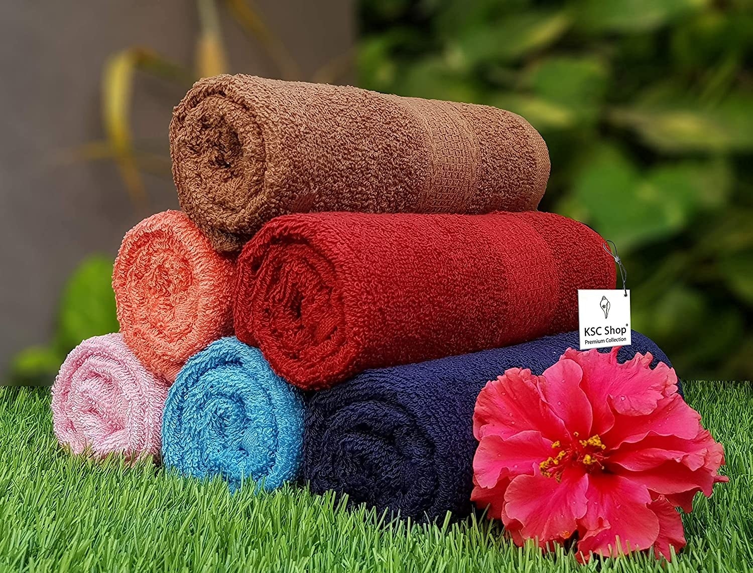 A set of towels on grass with a flower beside them