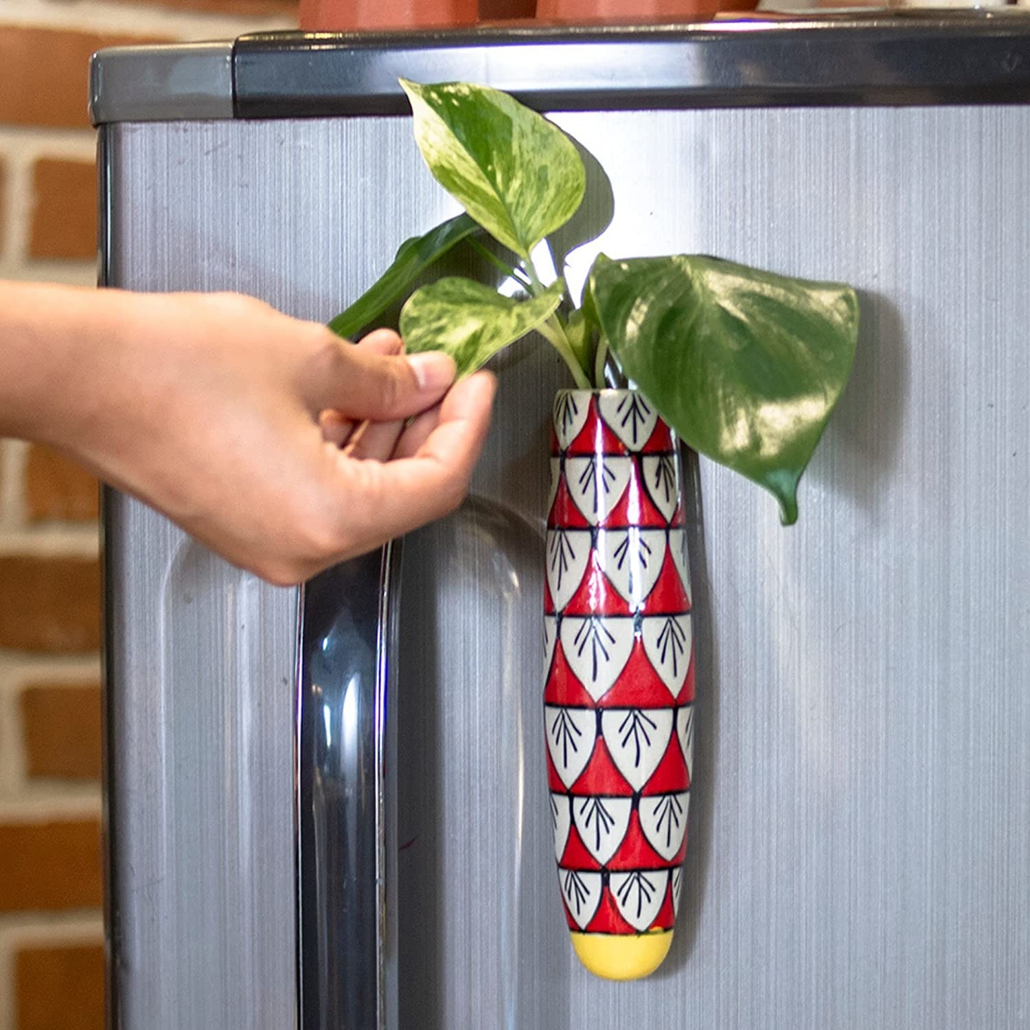A red and white fridge planter with a plant in it on a fridge