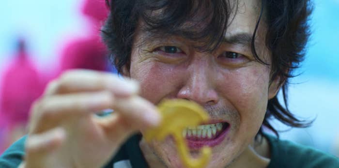 A close up of Gi-hun looking at the umbrella shape he has cut out of the dalgona candy