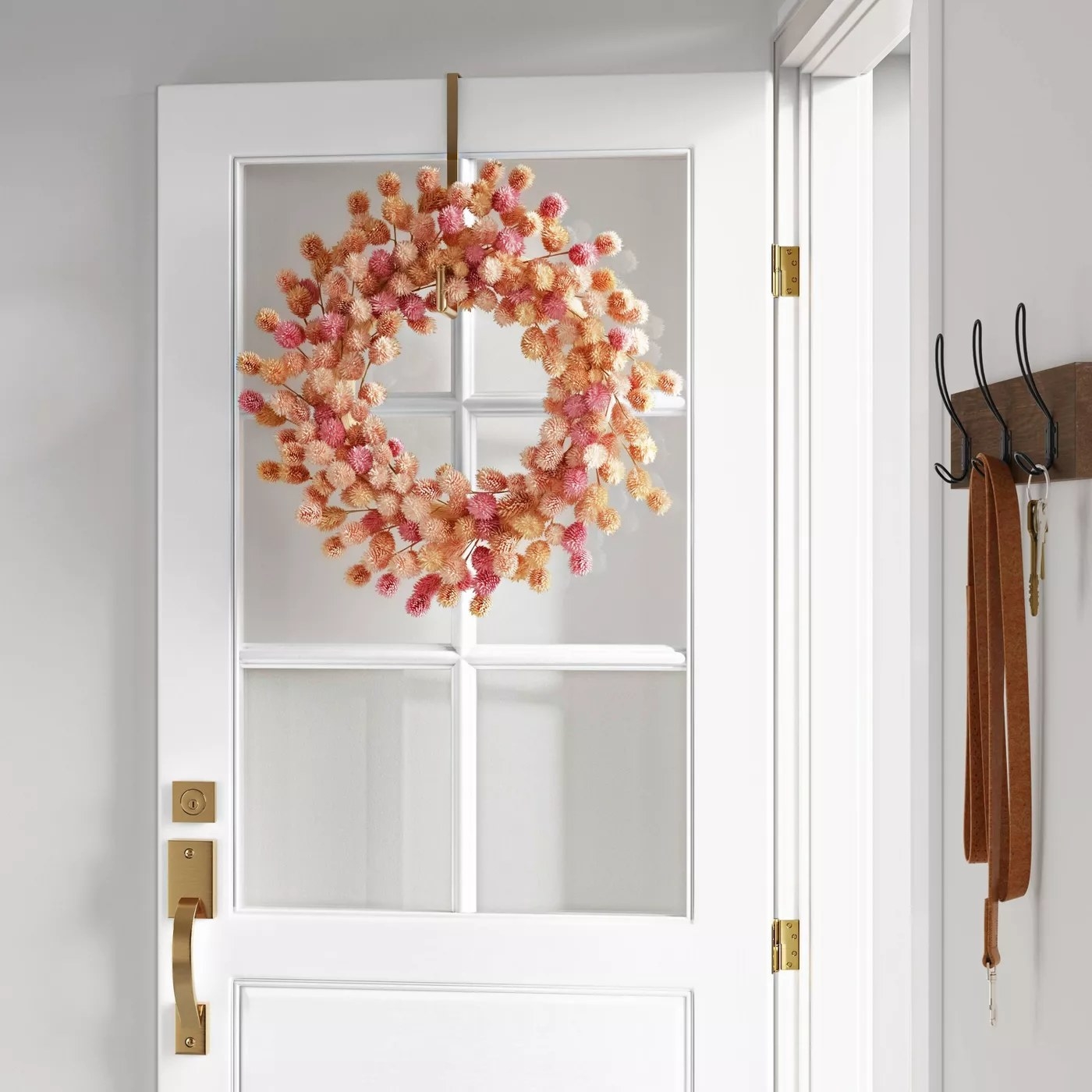 The wreath with faux flowers in various pink shades hanging on a door