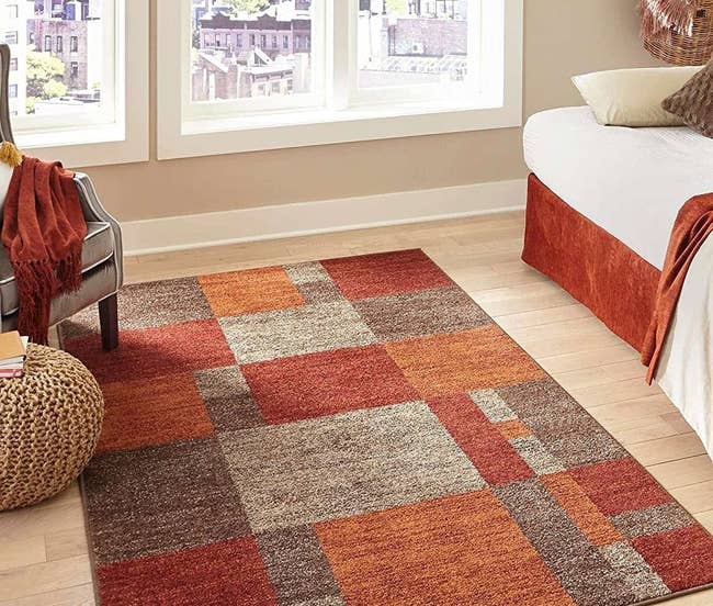 A red, orange, and neutral-colored checkered rug on the floor of a home