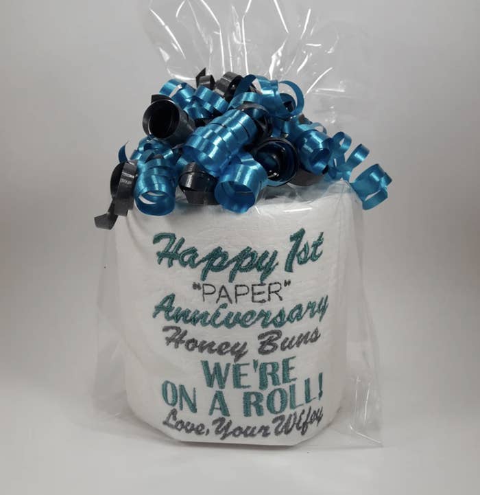 A product photo of toilet paper embroidered with "Happy 1st 'paper' anniversary Honey Buns. We're on a roll! Love, your wifey"