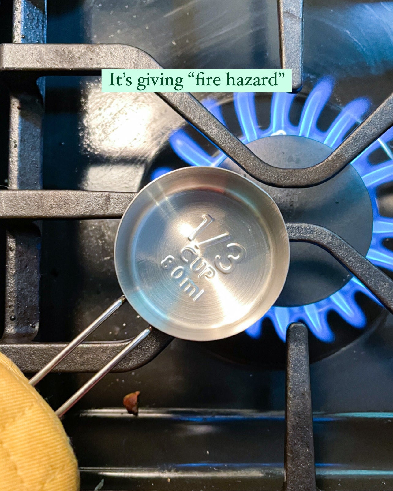 stainless steel measuring cup placed over the flame on a stove