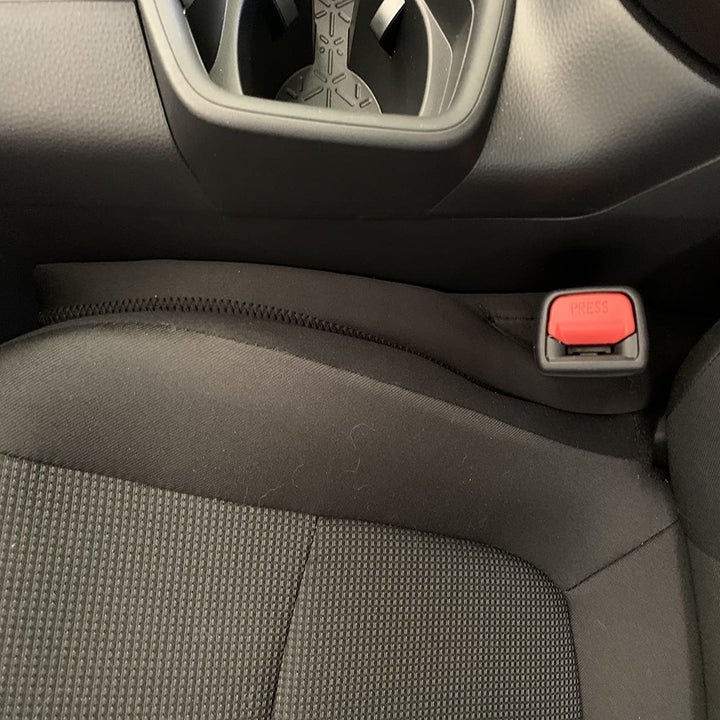 reviewer photo of the gap filler in between the seat and the center console with the seat belt holder in the built in pocket of the filler