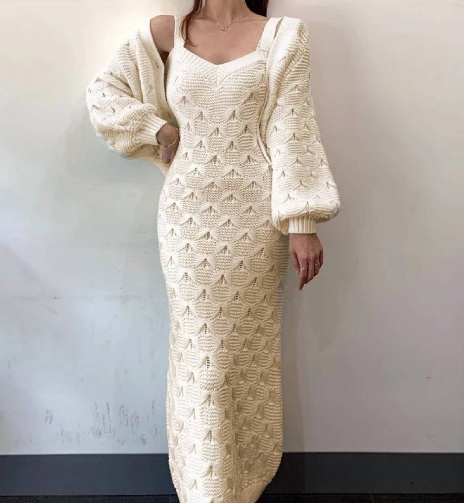 A model wearing the dress and sweater set in white