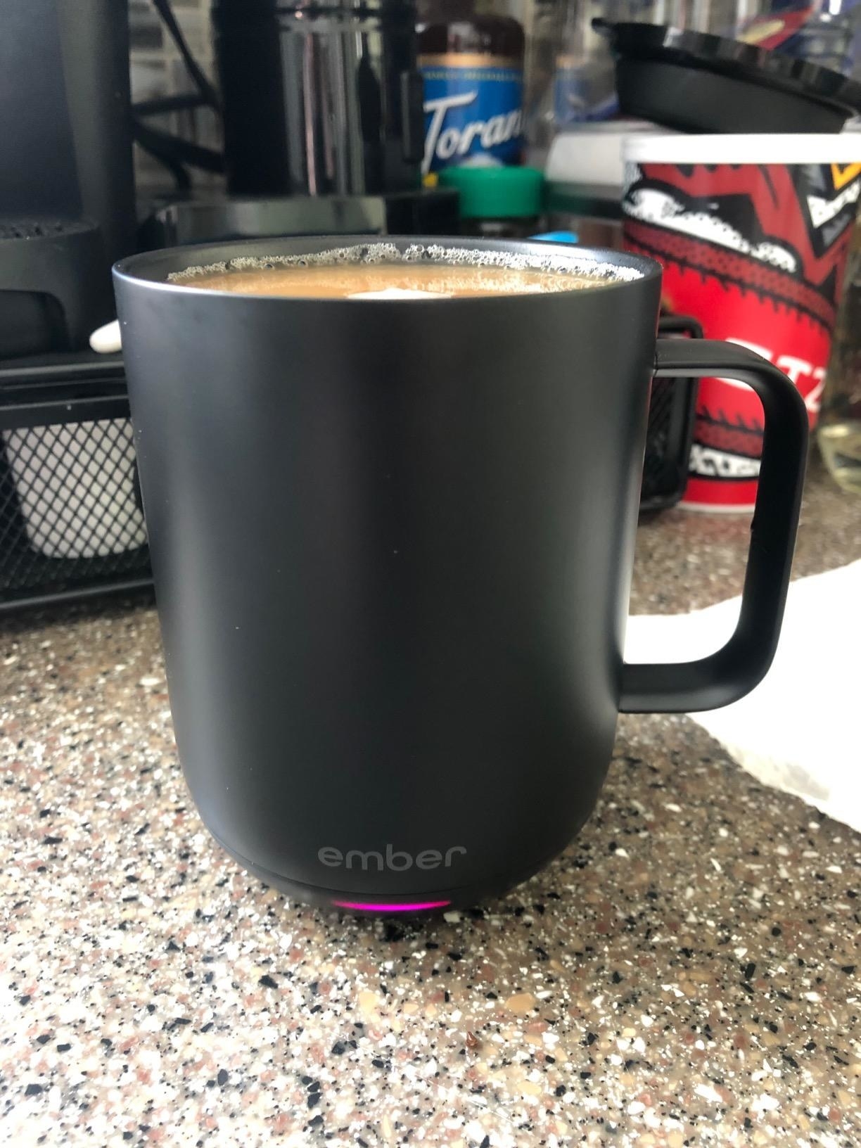 reviewer image of the mug on a counter with coffee in it and the bottom light lit up showing the heating functions in effect