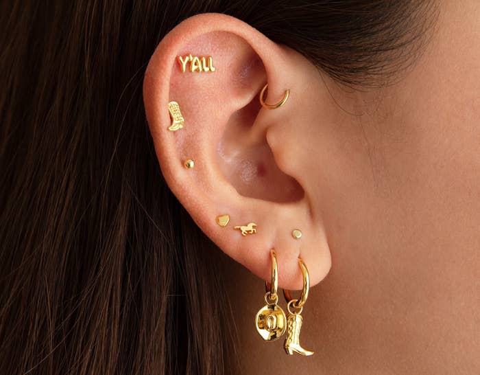 a model wearing a mix of Western-themed gold earrings