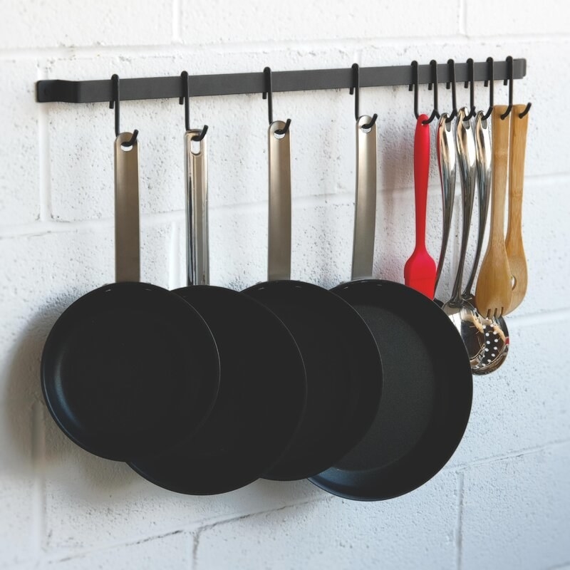 the pot rack with pots and utensils on a cinderblock wall