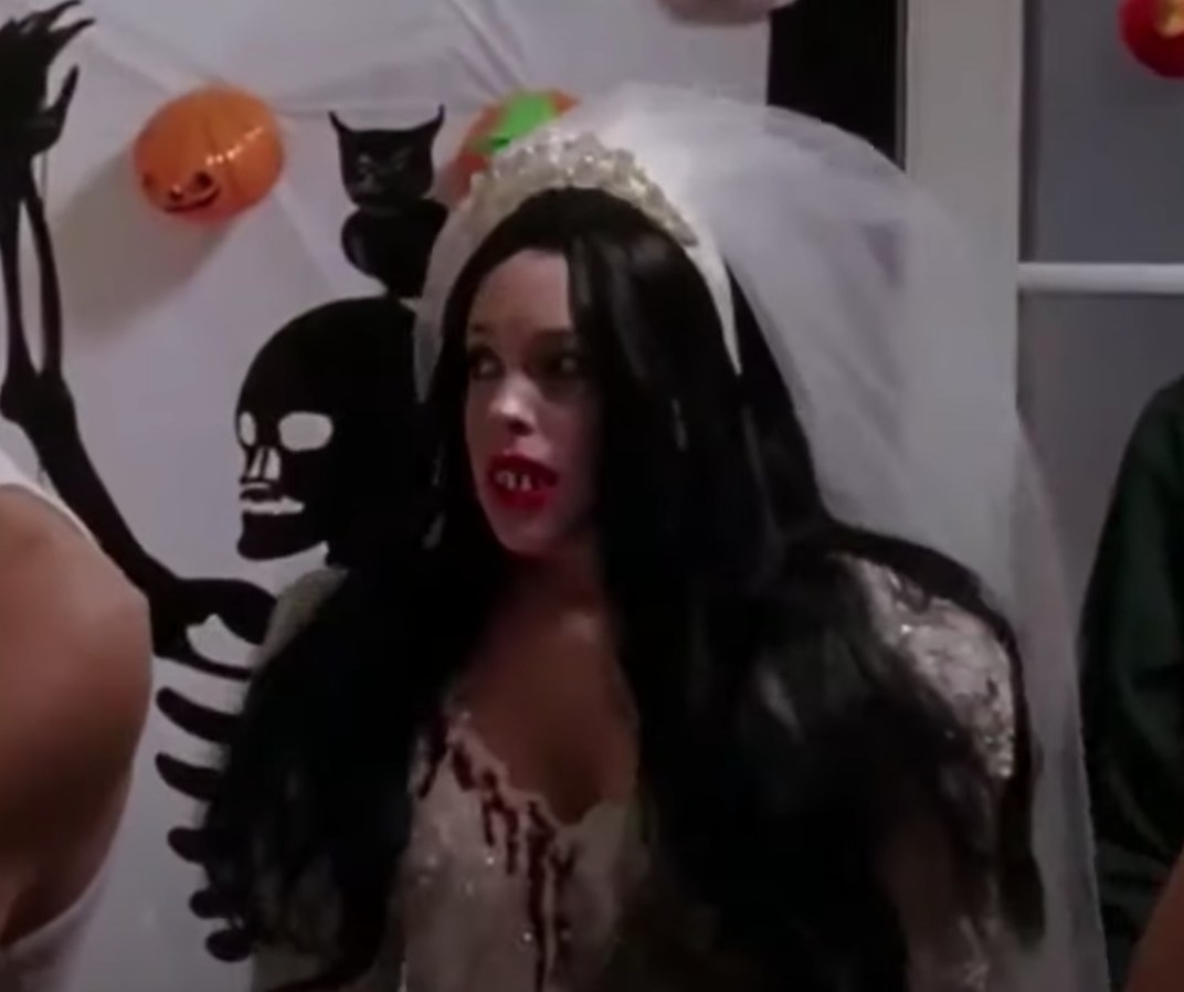 Cady wearing wedding gown covered in blood and veil with fake teeth and wig